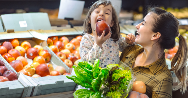 small girl eating apple in the store